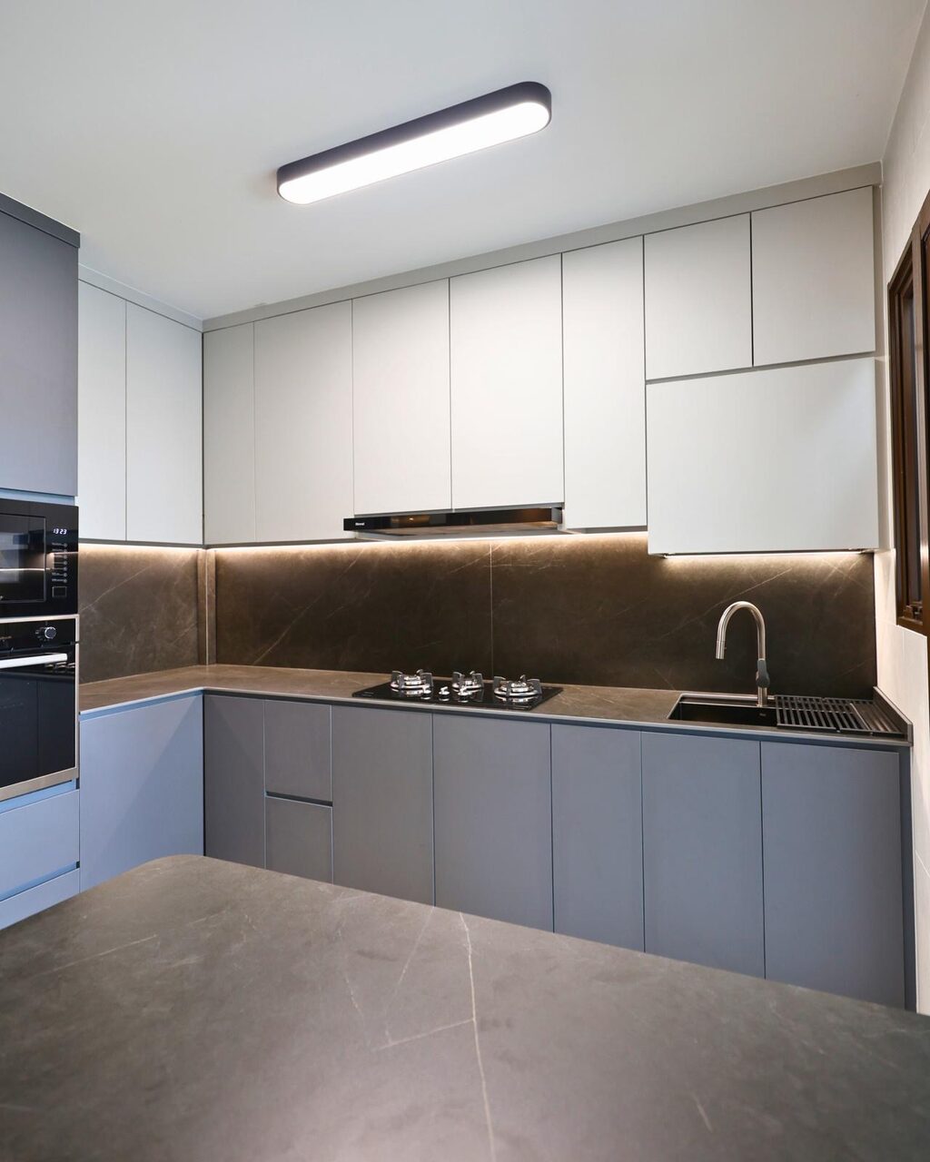 L-shaped two-tone kitchen with sintered-stone counter and backsplash